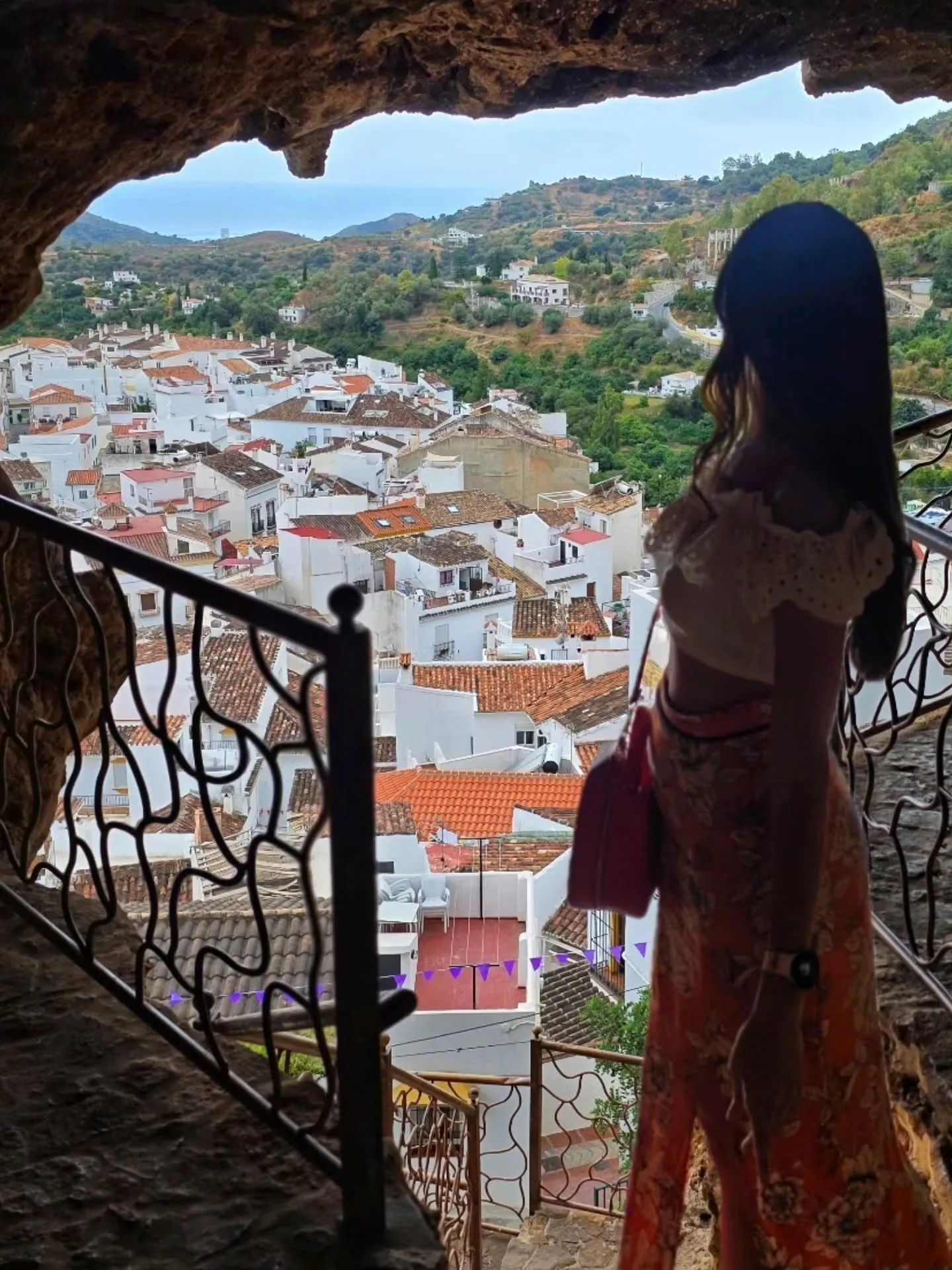 A white Andalusian village seen through the mouth of a cave balcony.